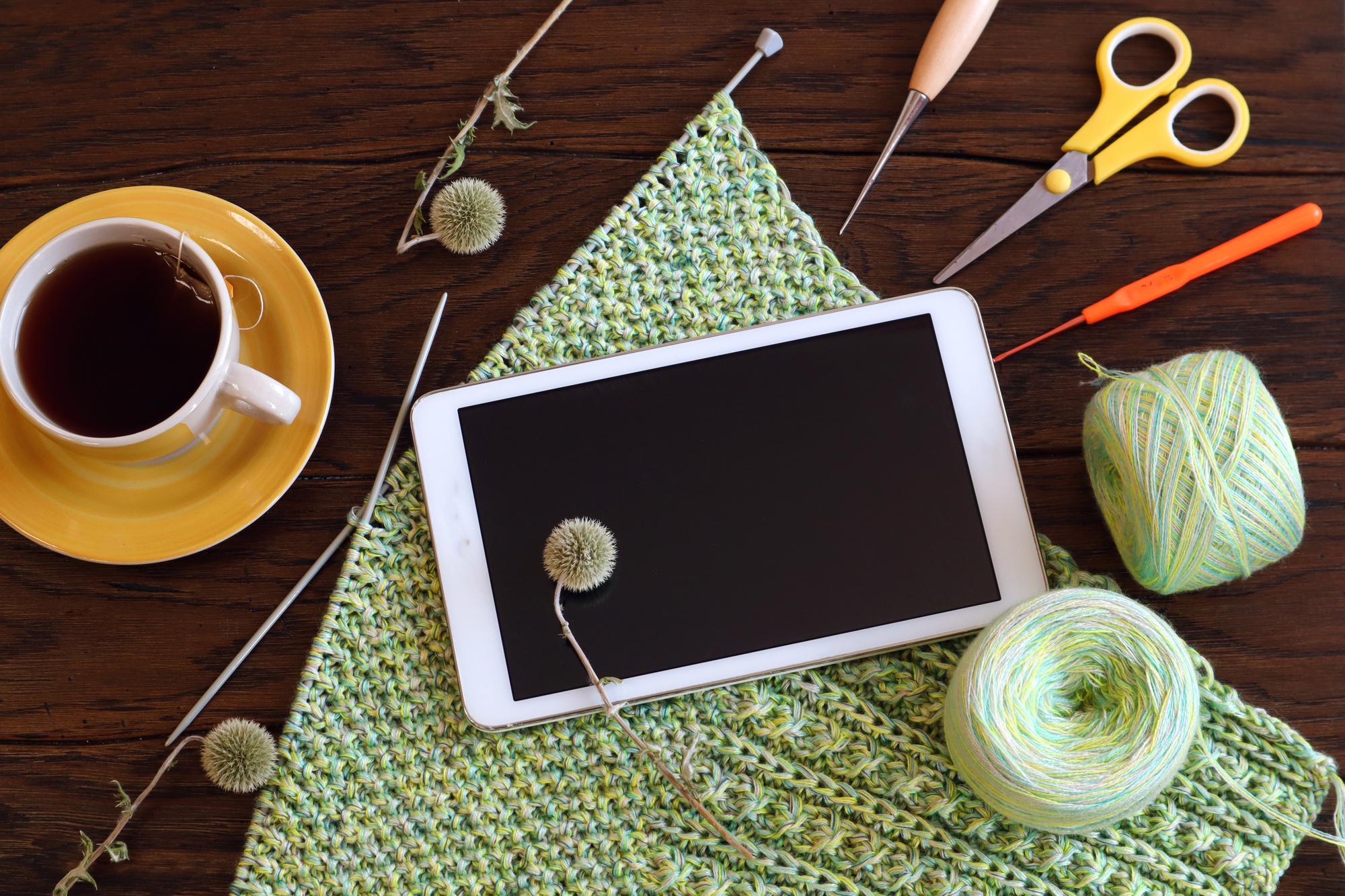 workspace with digitized embroidery pattern on tablet and spools of thread